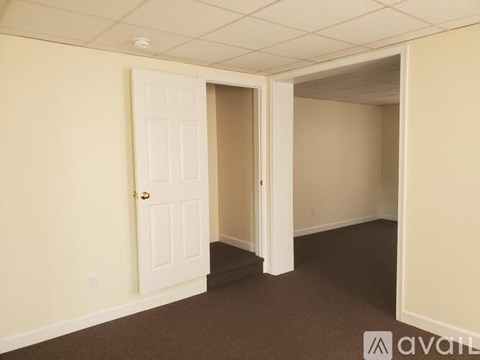 A room with a carpeted floor and a doorway leading to another room.