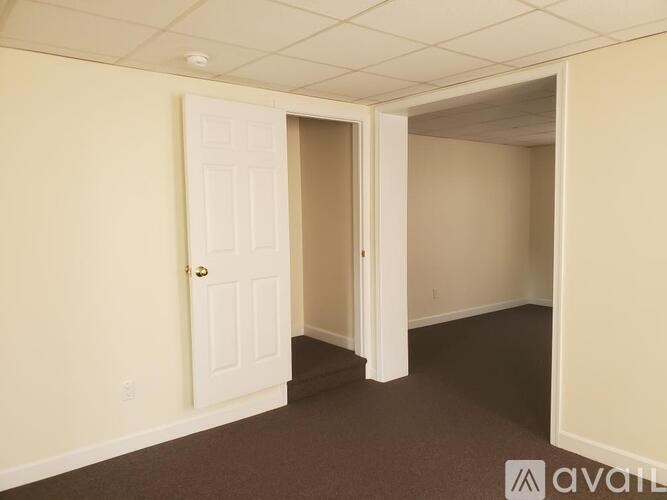 A room with a carpeted floor and a doorway leading to another room.
