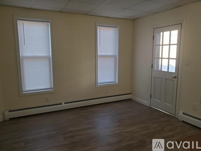 A room with two windows and a door is available for rent.