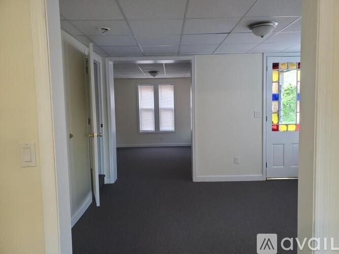 A room with a grey carpet and a stained glass window.