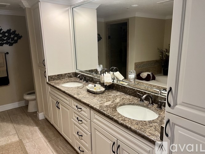 A bathroom with a marble countertop and white cabinets.