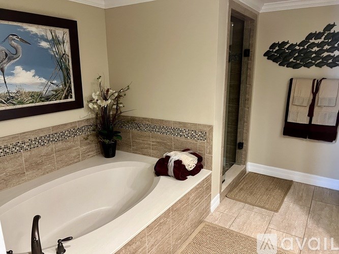 A bathroom with a large tub and a painting of a bird on the wall.