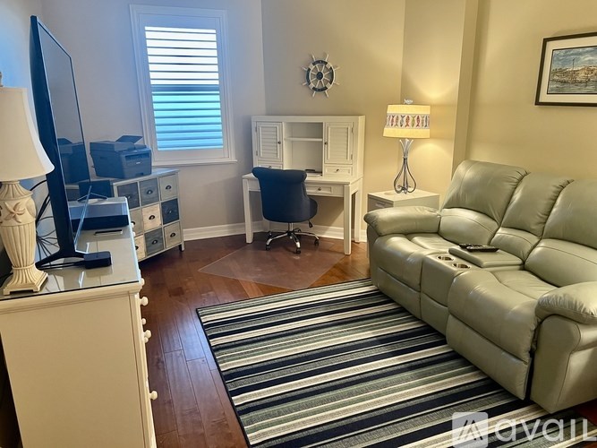 A living room with a striped rug and a grey couch.