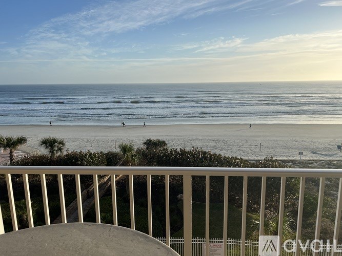 A beach scene with people on the sand and the ocean in the distance.