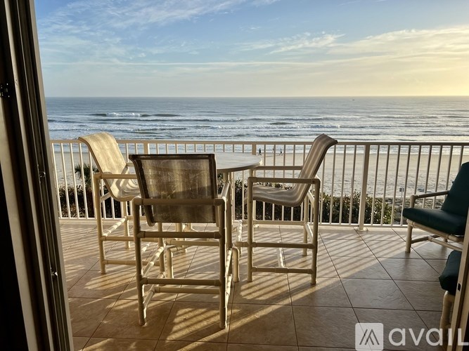 A balcony with chairs and a table overlooking the ocean.