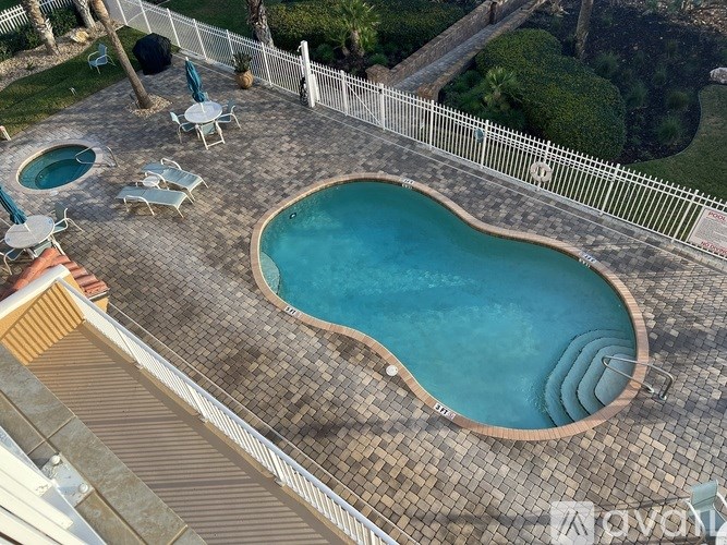 A small kidney-shaped pool with a wooden deck and a white fence.