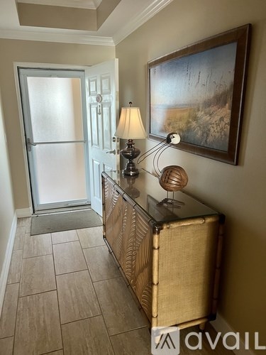 A hallway with a wooden cabinet, a painting, and a door.