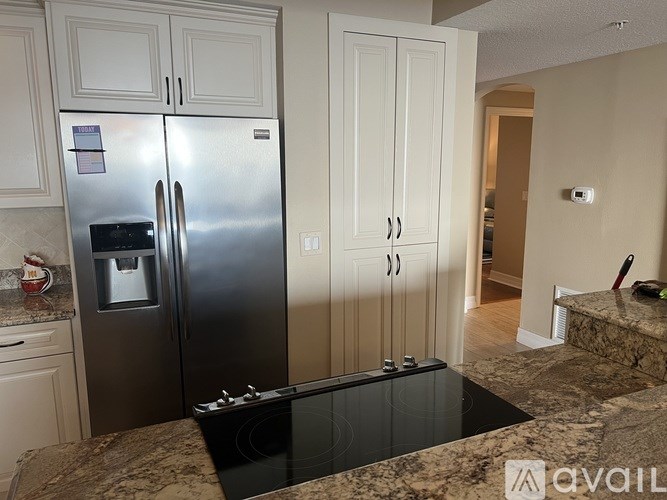 A kitchen with a granite countertop and a stainless steel refrigerator.