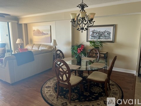A living room with a couch, chairs, and a table with a vase of flowers on it.