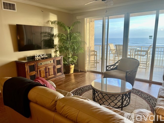 A living room with a couch, a table, and a television with a beach sign on it.