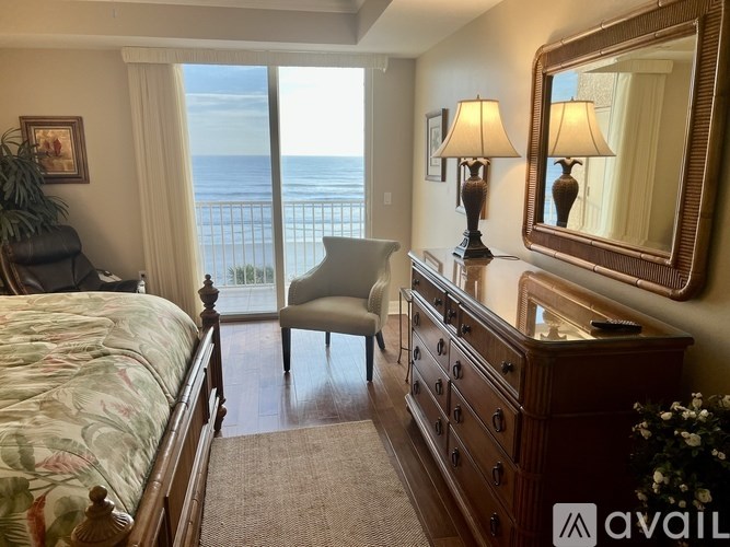 A bedroom with a bed, chair, and a dresser with a mirror and lamps.