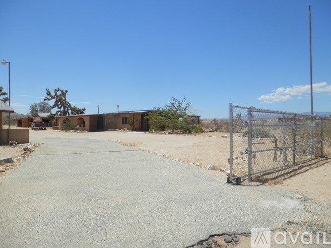 A concrete pathway leads to a gate in a fenced area.