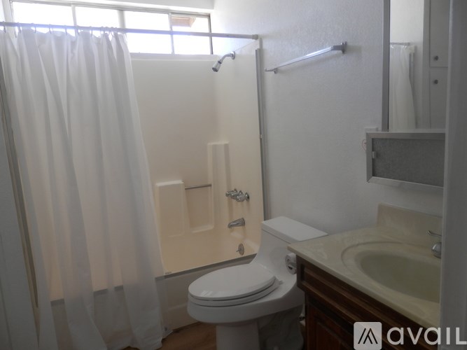 A white toilet in a bathroom with a white shower curtain.
