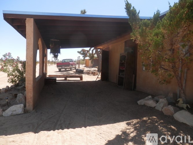 A house with a covered patio and a red car in the background.