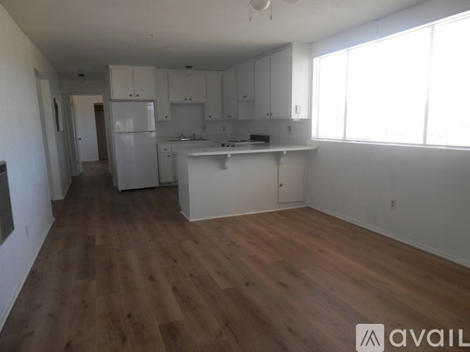 A kitchen with white cabinets and a wooden floor.