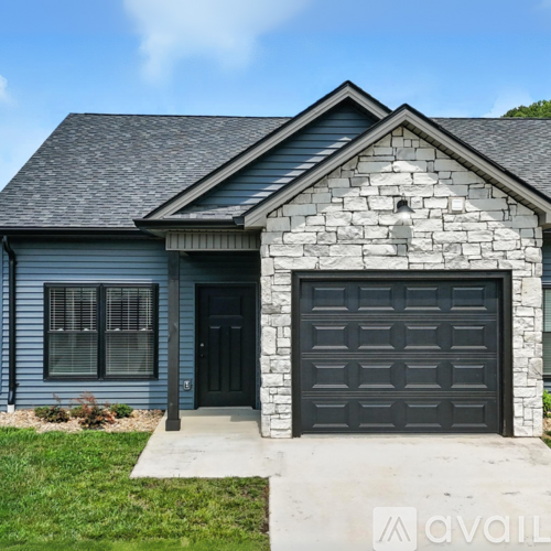 A house with a grey garage door and a stone facade.
