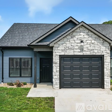 A house with a grey garage door and a stone facade.