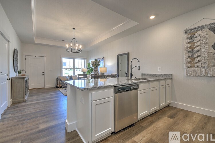 A modern kitchen with white cabinets and a wooden floor.