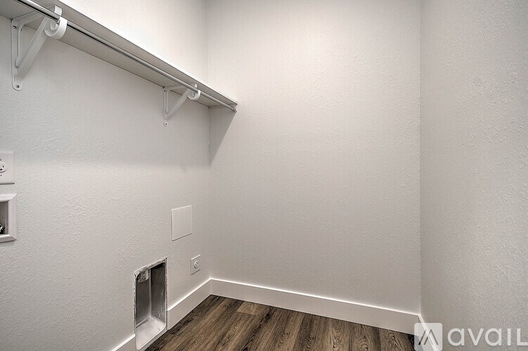 A white wall with a metal rail and hooks on it.
