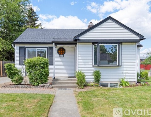 A house with a grey siding and a black roof is for sale.
