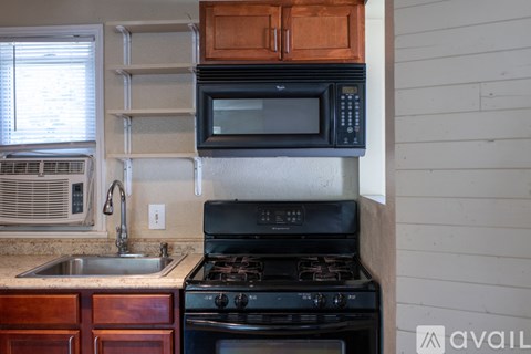 A kitchen with a black stove and a black microwave above it.