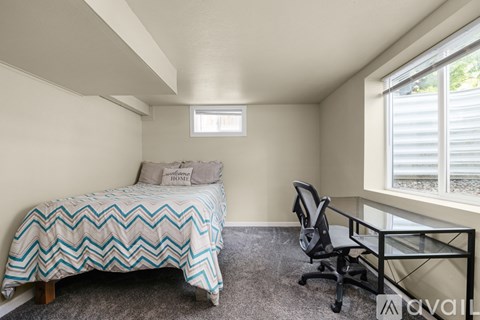 A bedroom with a bed, desk, and chair.