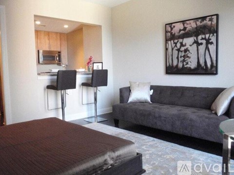A living room with a grey couch and a painting on the wall.