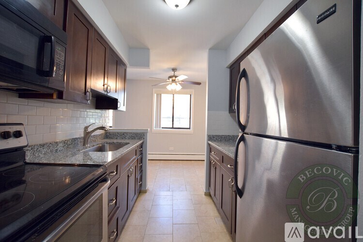 A kitchen with a stainless steel refrigerator and a granite countertop.