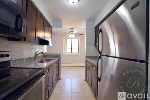 A kitchen with a stainless steel refrigerator and a granite countertop.