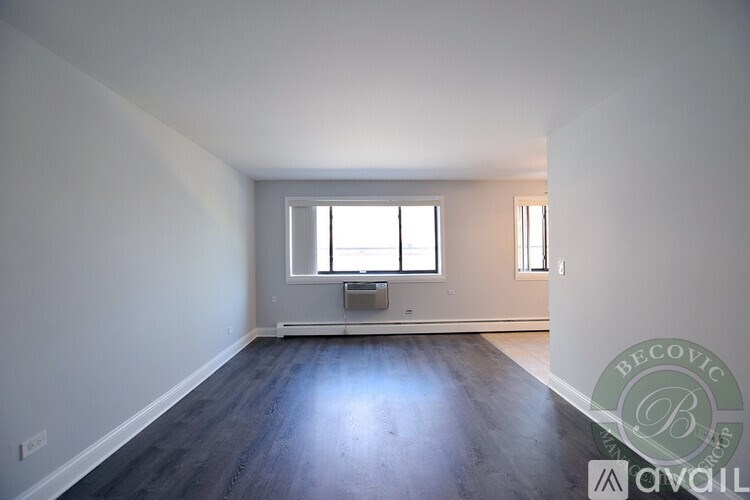 A room with a window and a wooden floor is available for rent.