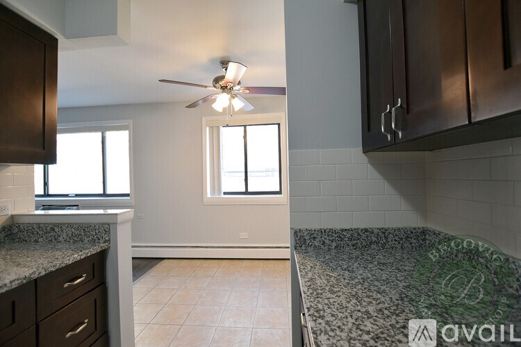 A kitchen with a marble countertop and a ceiling fan.