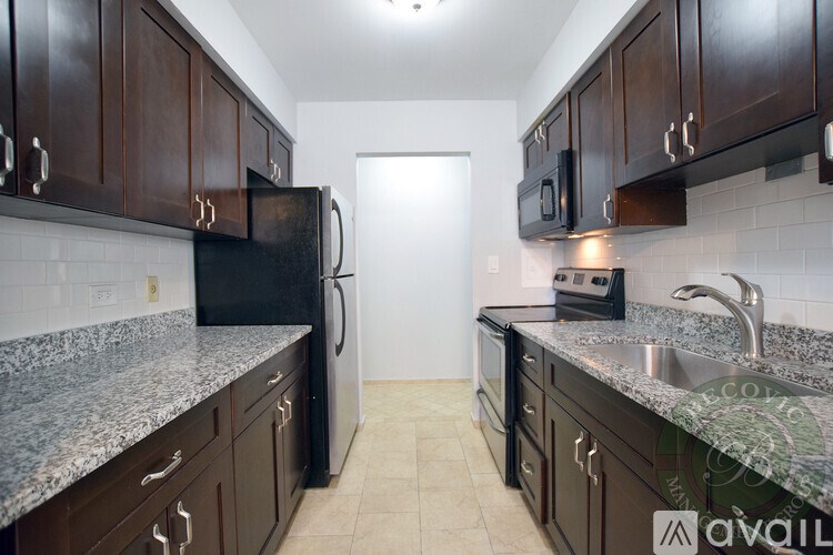 A kitchen with dark wood cabinets and granite countertops.