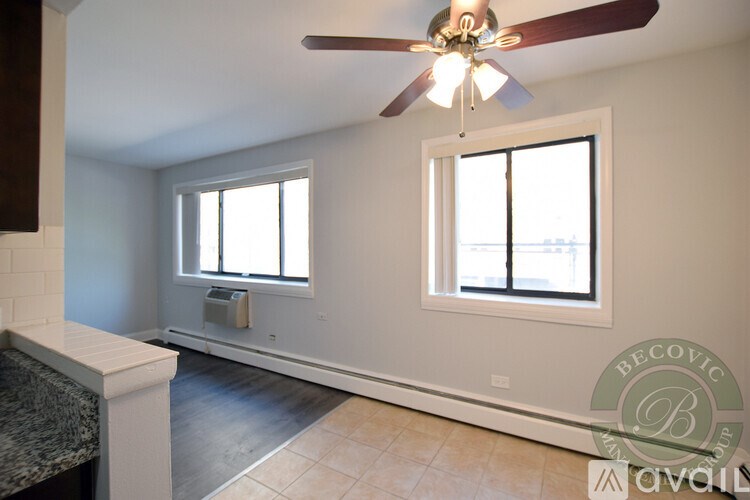 A room with a ceiling fan and two windows.