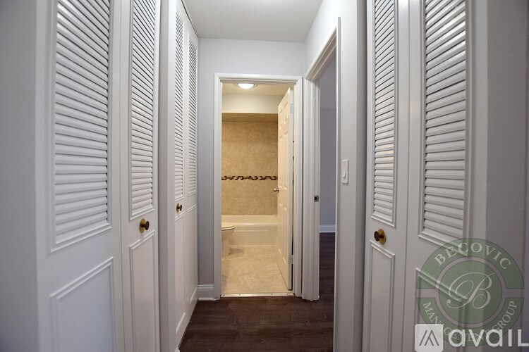 A hallway with white doors and a brown carpet.