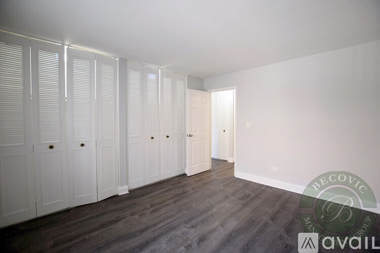 A room with white cupboards and a wooden floor.