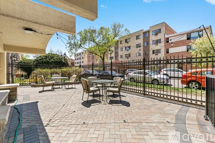 A patio with a table and chairs is surrounded by a black metal fence.
