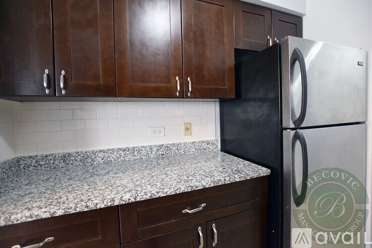 A kitchen with a granite countertop and dark brown cabinets.