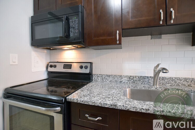 A kitchen with a black microwave above an oven and a granite countertop.