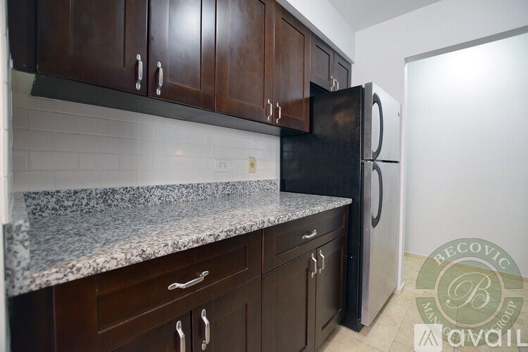 A kitchen with a black refrigerator and brown cabinets.