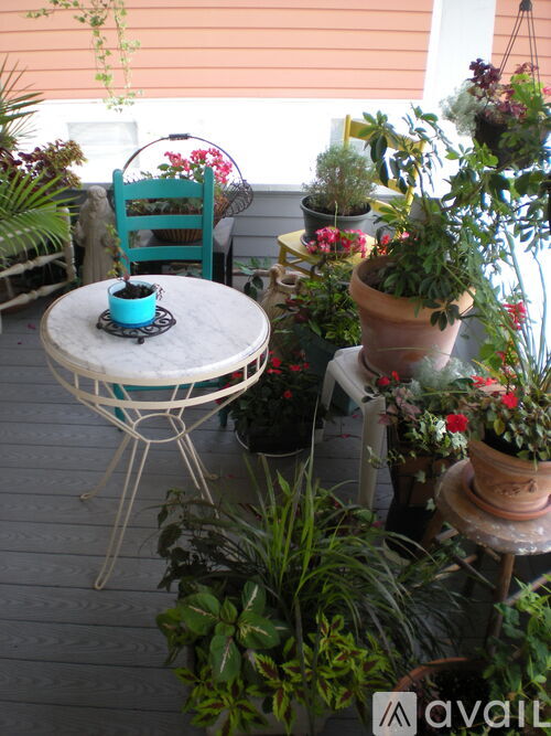 A balcony with a table, chairs, and potted plants.