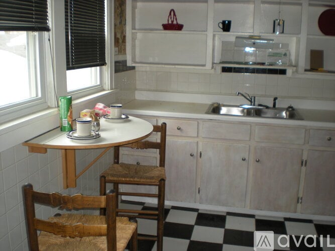A kitchen with a checkered floor and a table with two chairs.