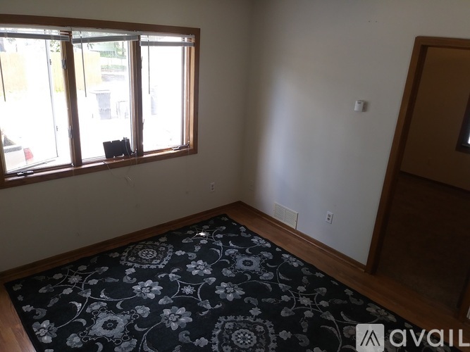 A room with a rug on the floor and a window with blinds.