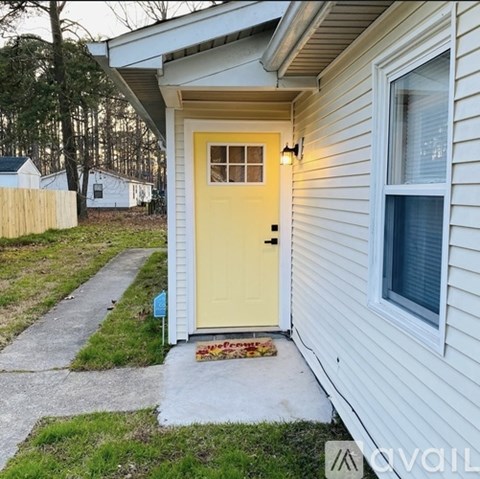 A white house with a yellow door and a small porch.