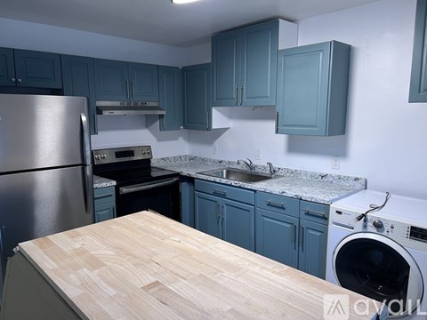 A kitchen with a wooden counter top and a stainless steel refrigerator.