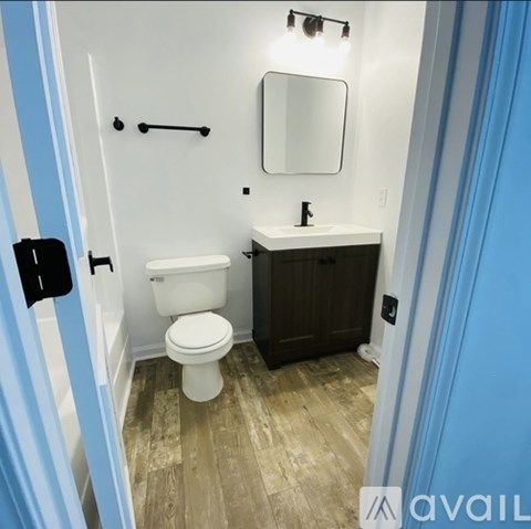 A bathroom with a toilet, sink, and mirror.