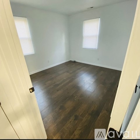 A room with wooden flooring and white walls.