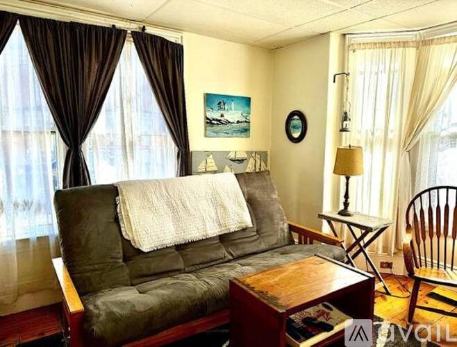 A living room with a grey couch, a wooden coffee table, a lamp, and a painting on the wall.