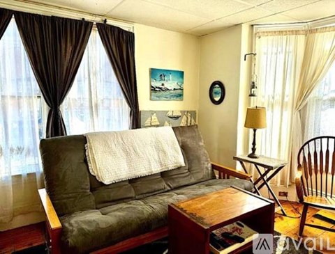 A living room with a grey couch, a wooden coffee table, a lamp, and a painting on the wall.