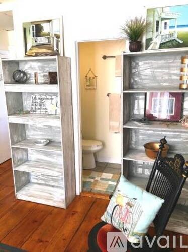 A room with a chair and a shelf with a mirror on it.