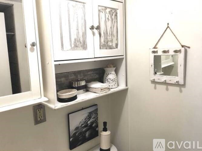 A bathroom with a white cabinet and a mirror.